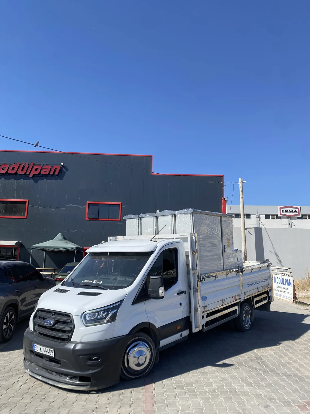 Sanayi sitesinde paketli palet yükü taşıyan nakliye aracı
